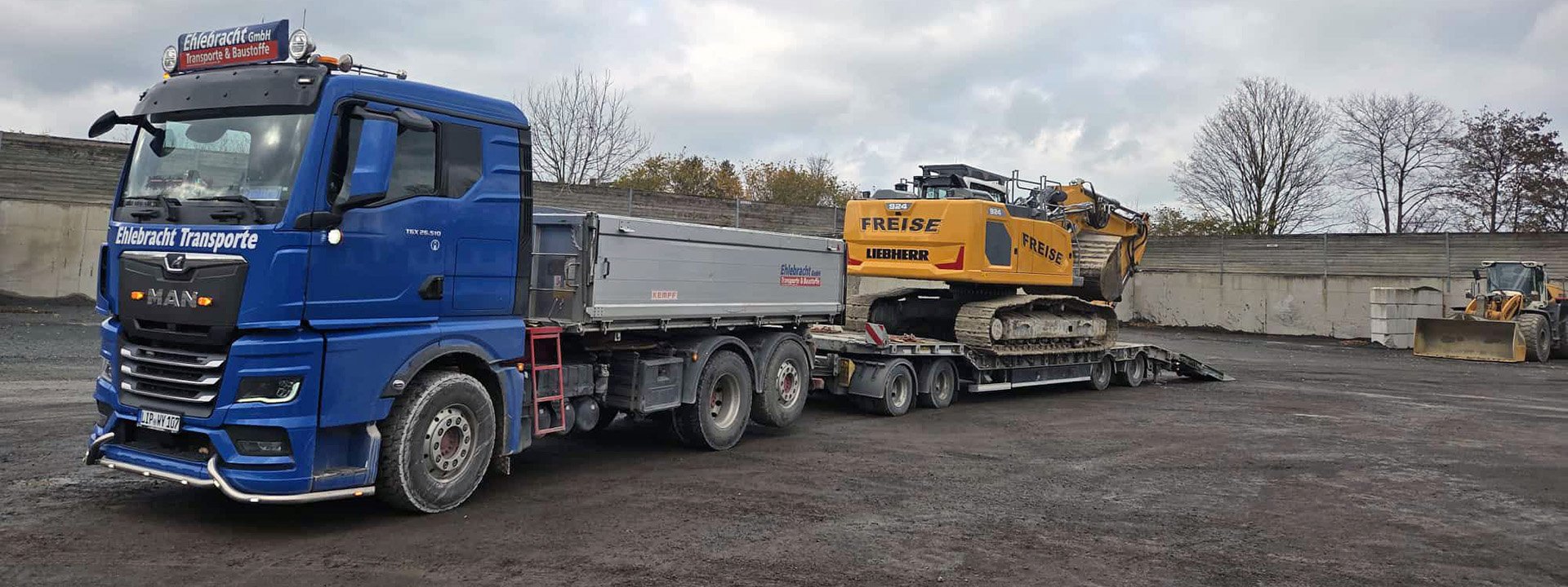 LKW von Ehlebracht Transporte transportiert Baumaschine auf Tieflader im Baustellenbereich