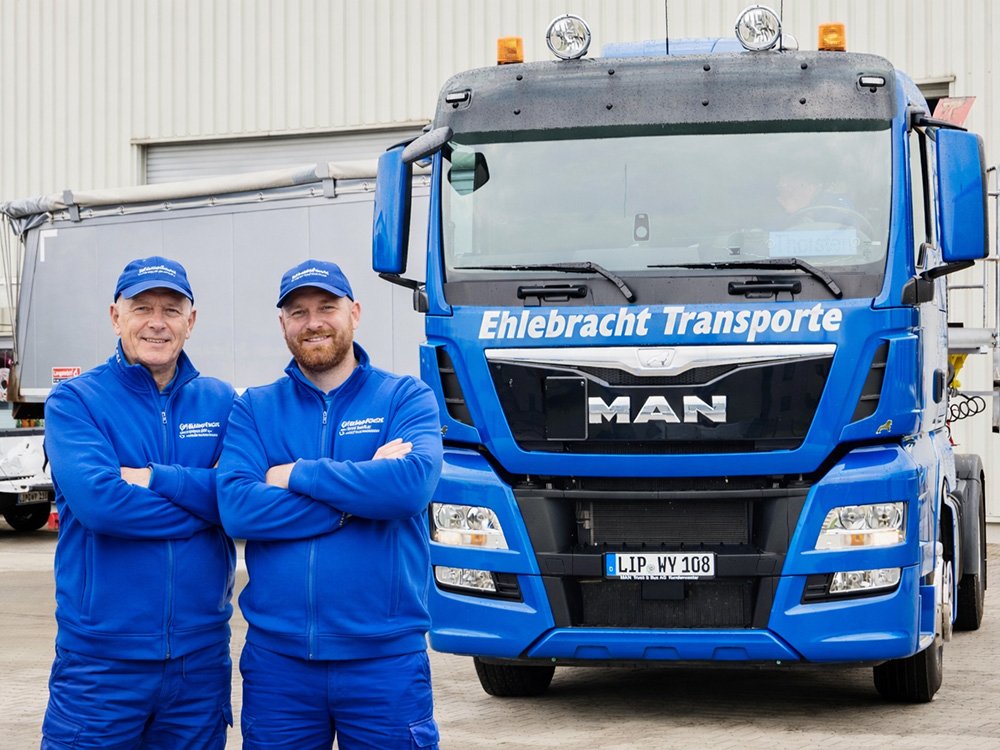 Zwei Kraftfahrer von Ehlebracht Transporte vor LKW im Baustellenverkehr